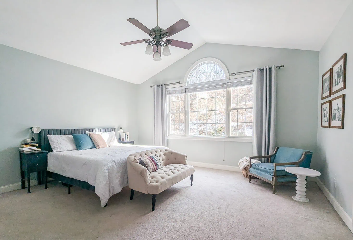 bedroom with cathedral ceiling, bed with white quilt, and blue armchair.