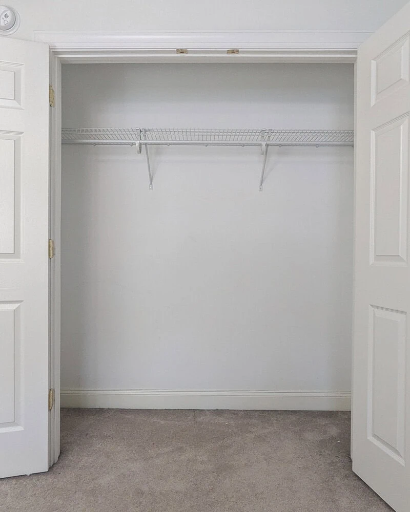 empty closet with one hanging rod and one wire shelf.