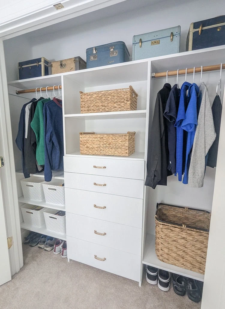 filled closet organizer with clothes, baskets, and vintage train cases as storage.