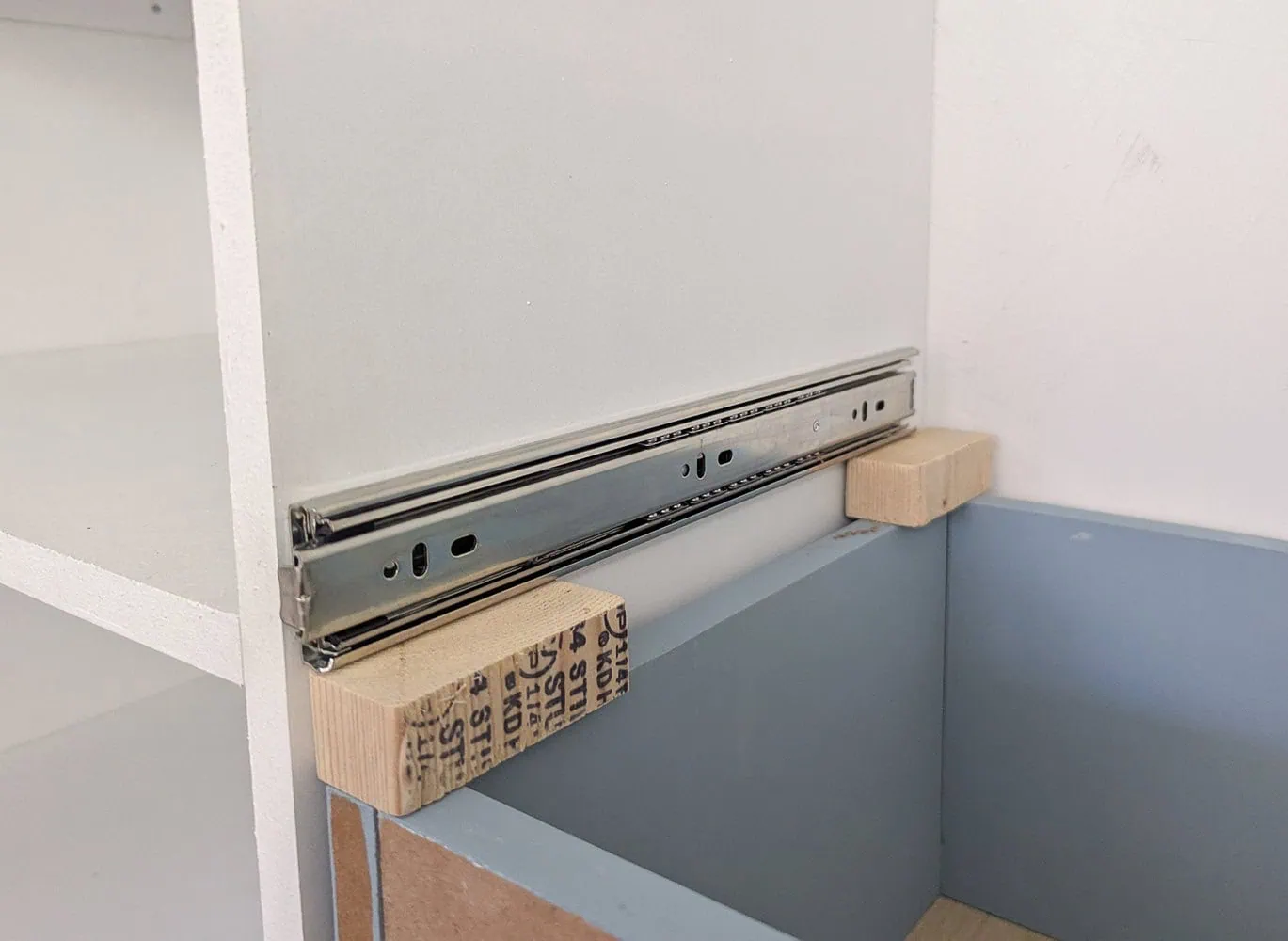 using scrap wood to hold drawer slide at correct height.