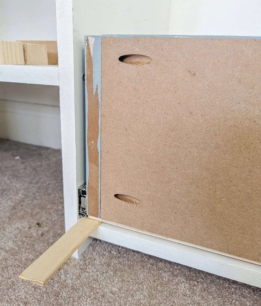 a scrap of plywood holding the drawer at the correct height while installing drawer slides.