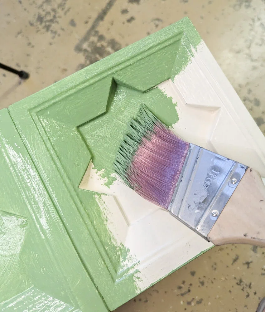 painting the nightstand green with a paint brush.