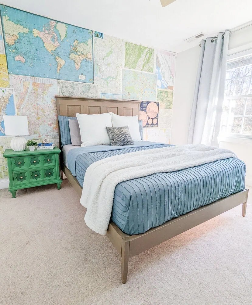 DIY bed next to green nightstand and map wall.