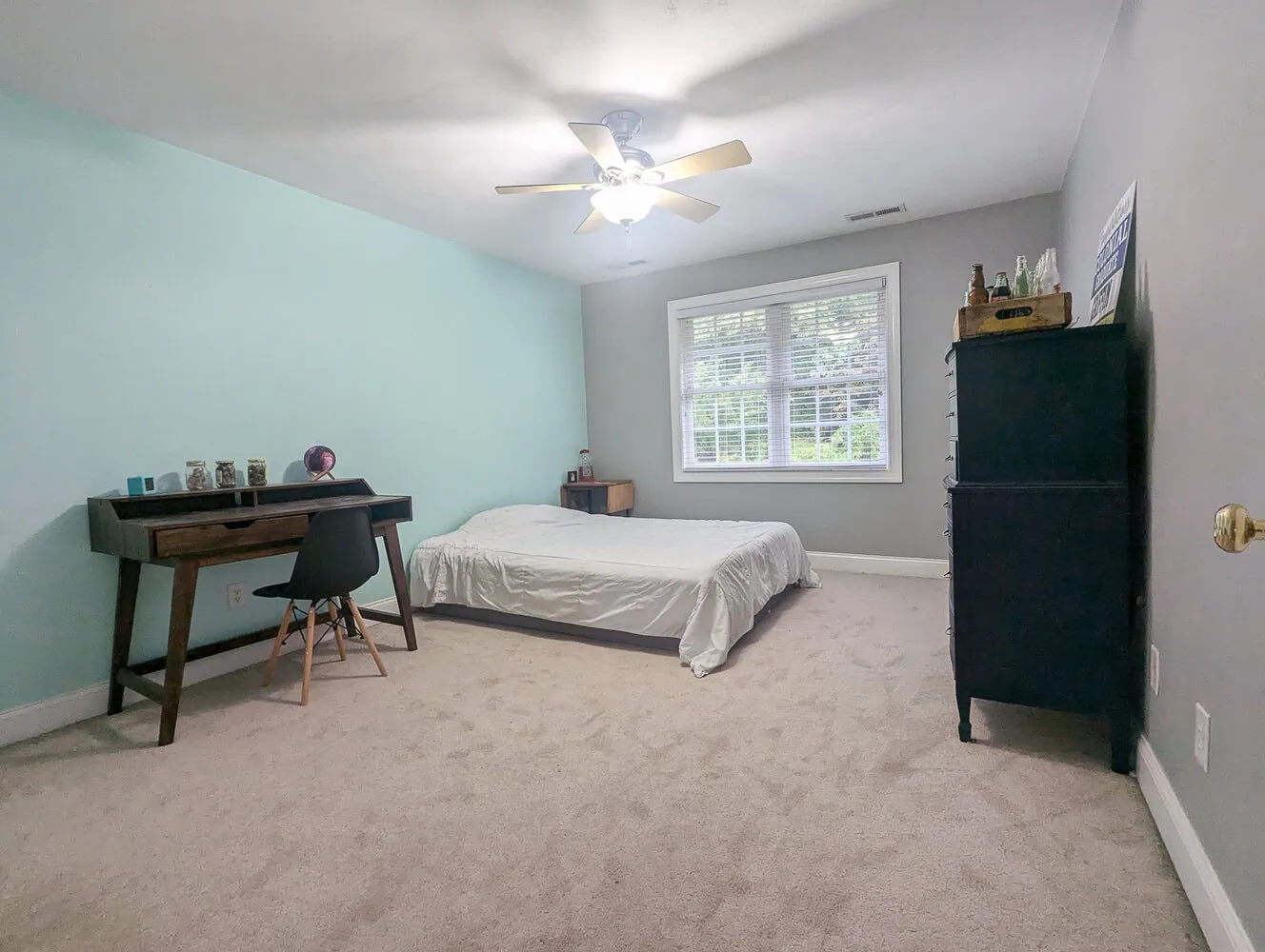 bland bedroom with blue and gray walls, mattress on floor, and blank walls. 