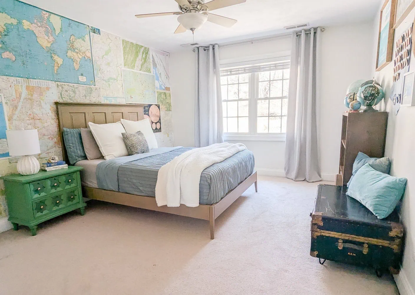 boys travel bedroom with DIY bed, map wallpaper, green nightstand, and trunk bench.