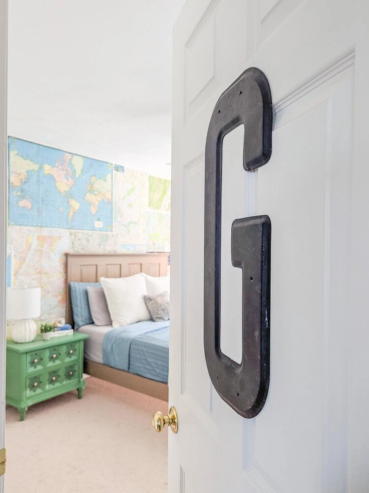 looking through door with vintage marquee letter into boys vintage travel bedroom.