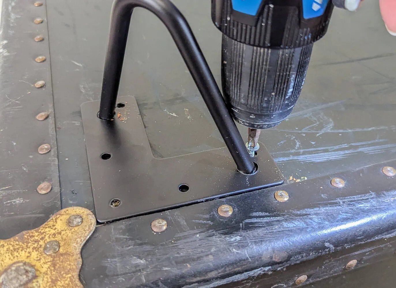 Screwing legs to the bottom of a vintage foot locker.