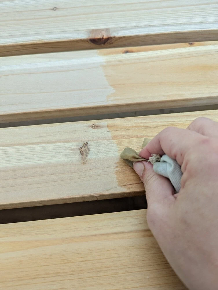applying wood oil to cedar with a rag.