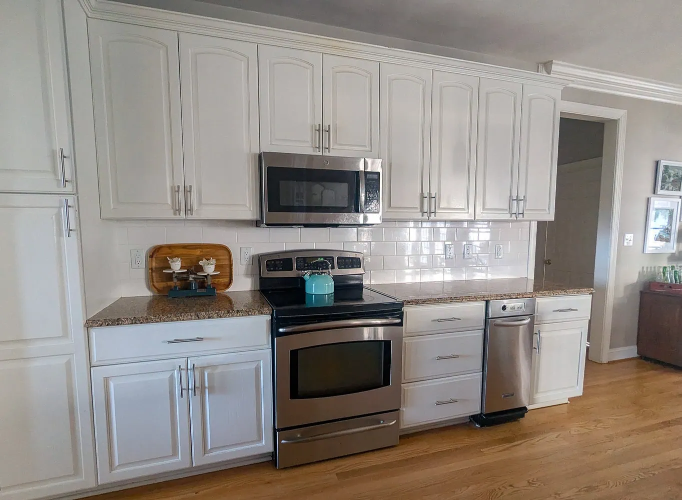 wall of white cabinets with white subway tile and brown granite.