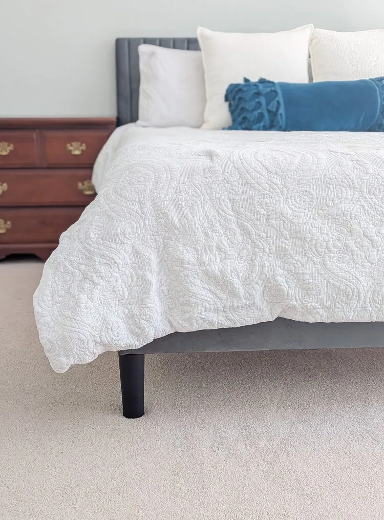 upholstered bed with black plastic legs.