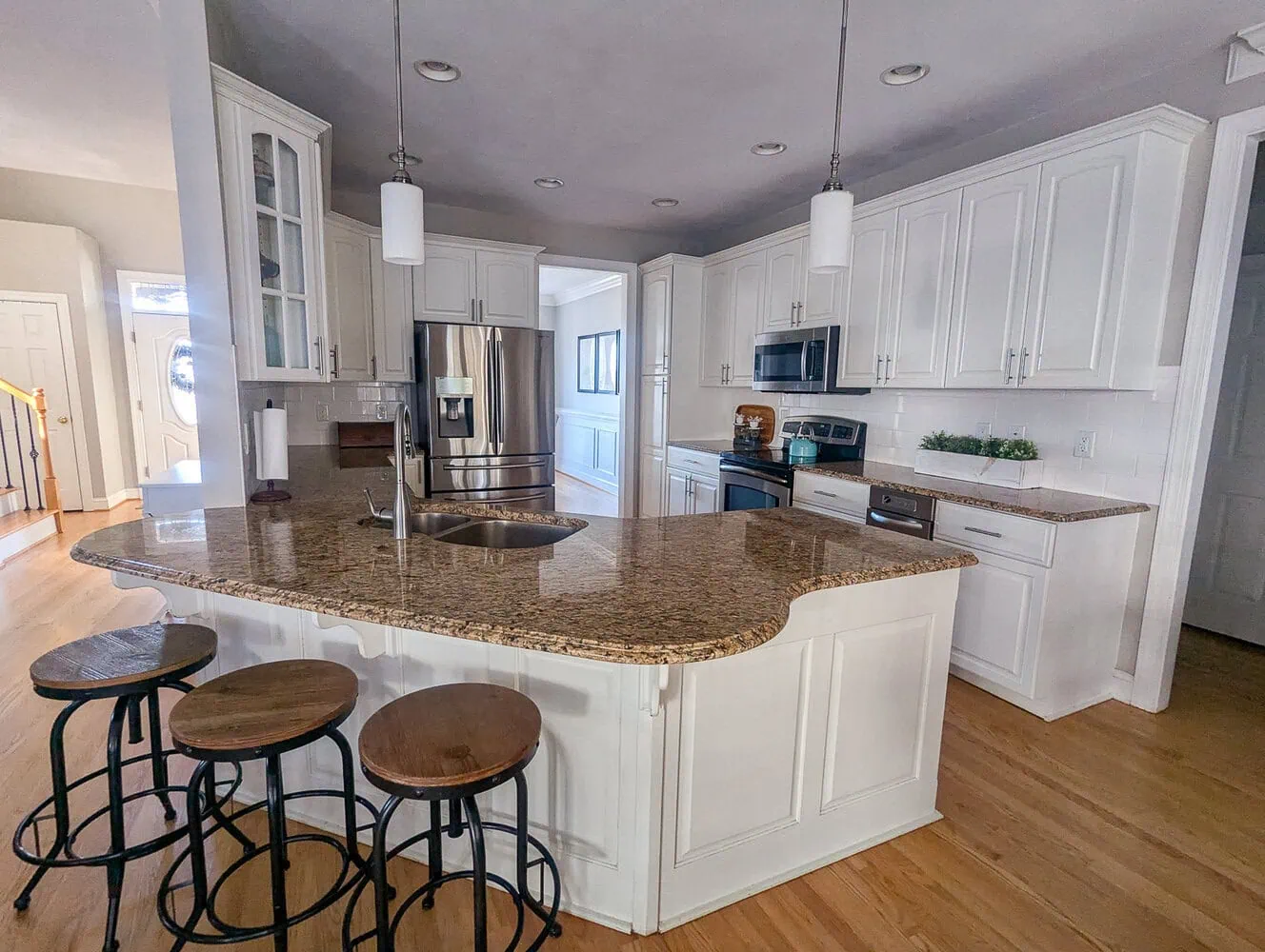 kitchen with white cabinets, brown granite, and stainless steel appliances. 