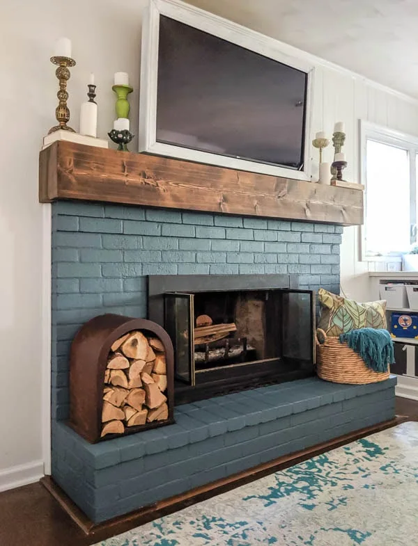 blue painted brick fireplace with painted fireplace doors and diy mantel.