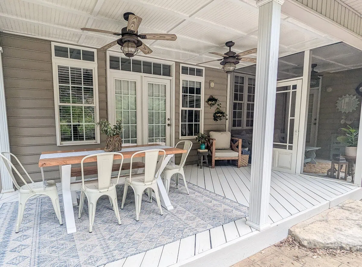covered porch with a variety of wood outdoor furniture.