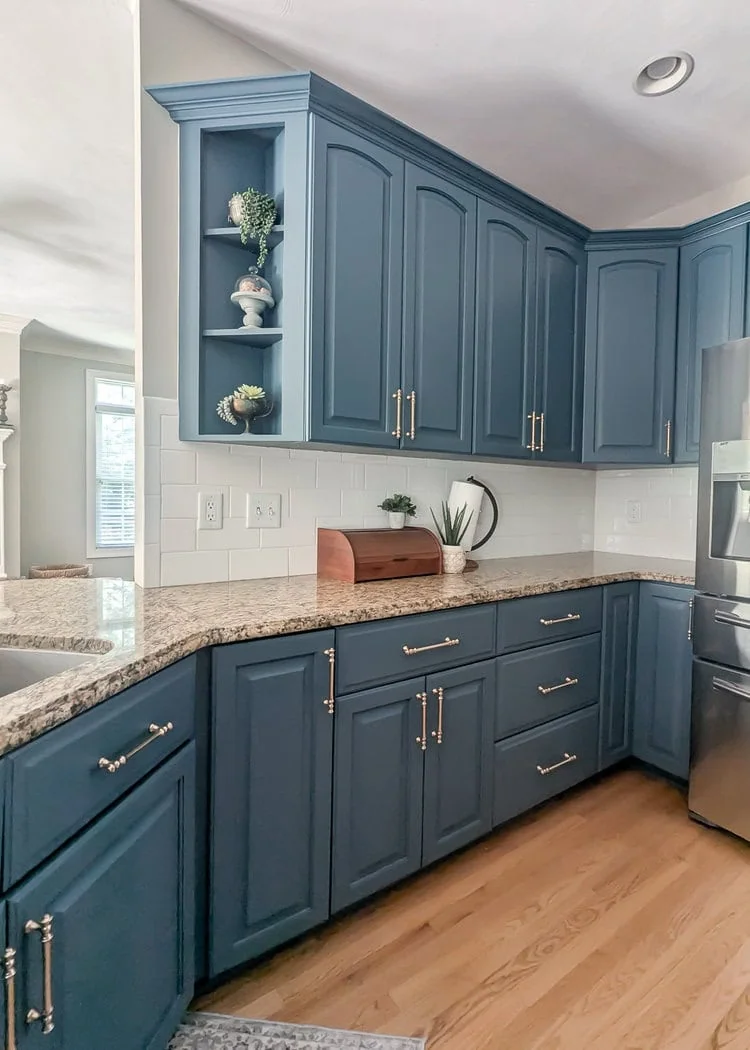 Blue kitchen cabinets with glass door removed to create open shelves.