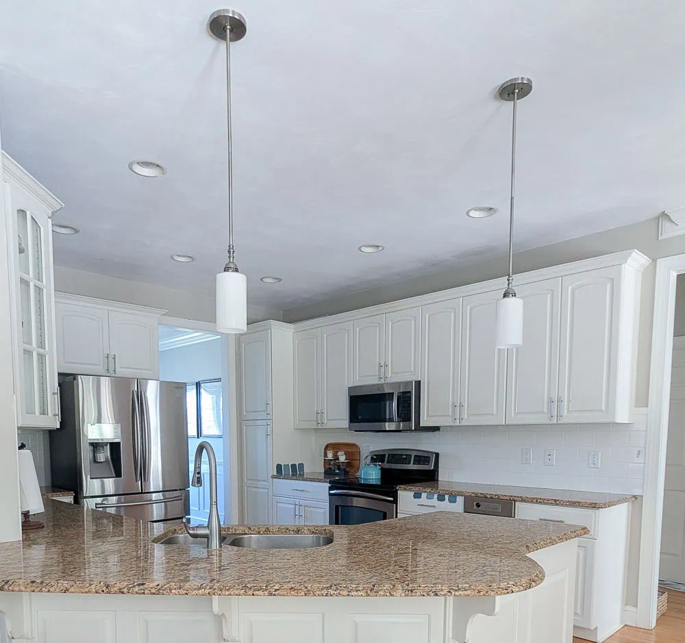 White kitchen with brushed nickel pendant lights.