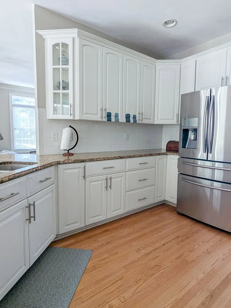 white kitchen cabinets with one glass door on end.