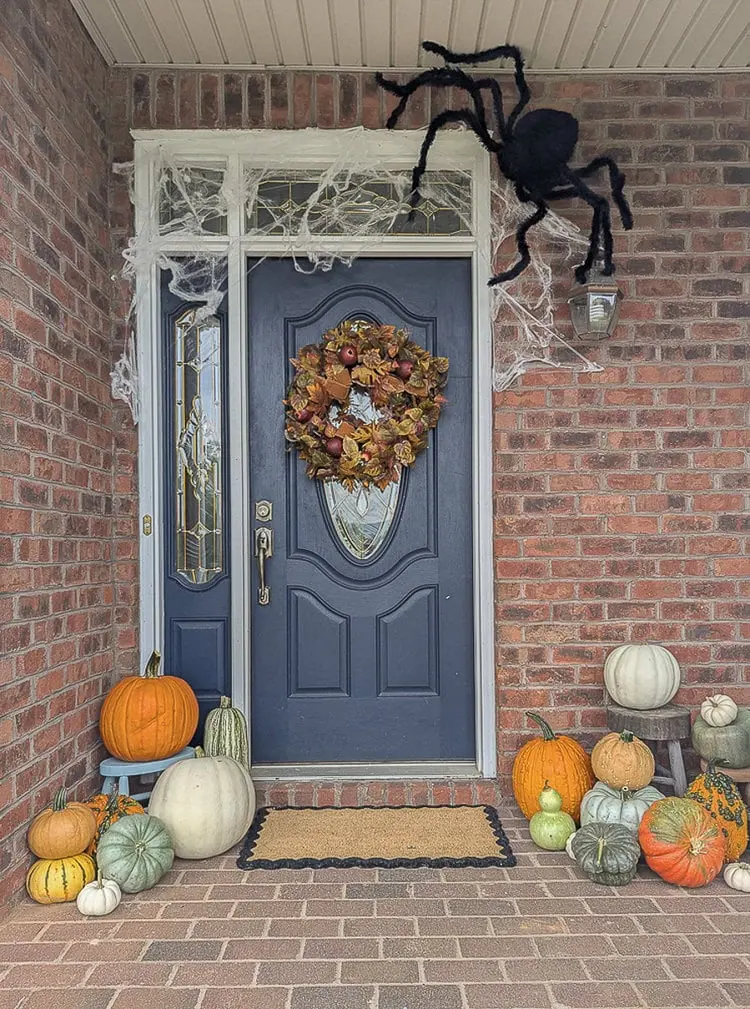Halloween front porch with huge spider and spider web over door.