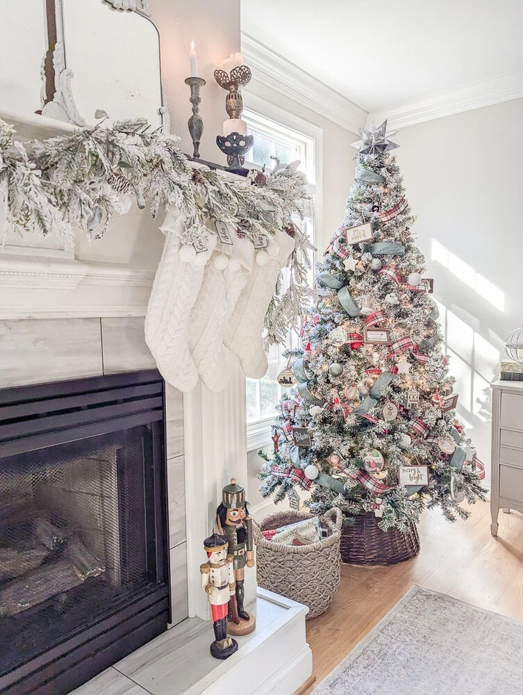 Christmas mantel with flocked garland next to a flocked Christmas tree decorated with red and green decorations.
