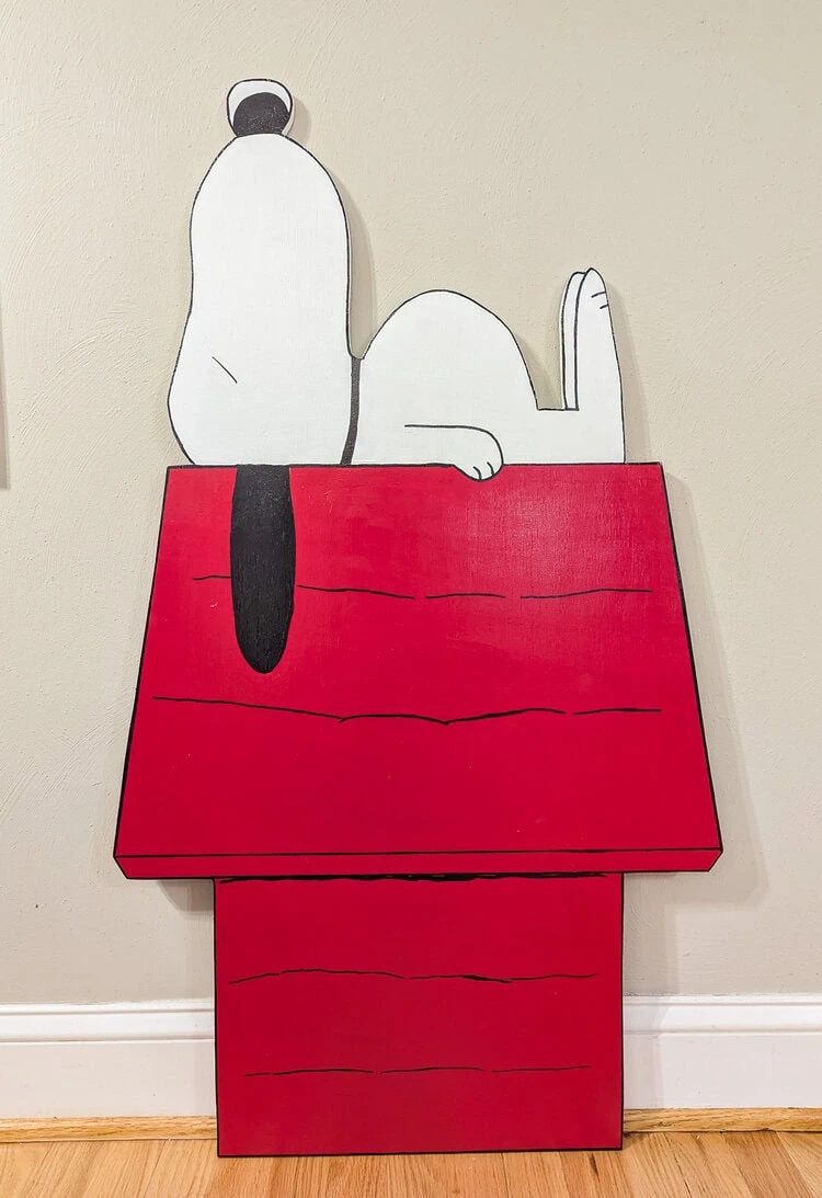 Wood cutout of Snoopy on his doghouse after the details are painted.